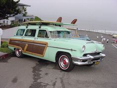 an old green station wagon with surfboards on top