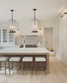 a large kitchen with an island and four stools in front of the countertop