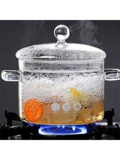 a glass pot filled with liquid sitting on top of a stove burner next to an orange slice