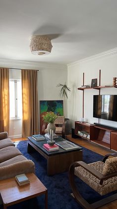 a living room filled with furniture and a flat screen tv on top of a wooden table