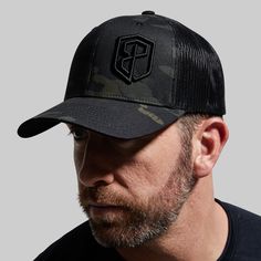 a man with a beard wearing a black trucker hat and looking at the camera