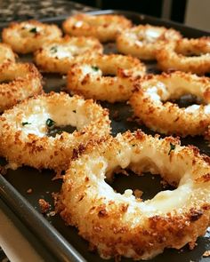 fried onion rings on a baking sheet ready to be cooked in the oven with parmesan cheese