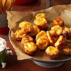 there are some fried food in a bowl on the table next to a green cup