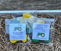 two plastic bags filled with green and yellow farm themed birthday party favors sitting on top of dry grass