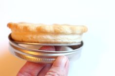 a person is holding a tin can with food in it and there is a small piece of bread on top