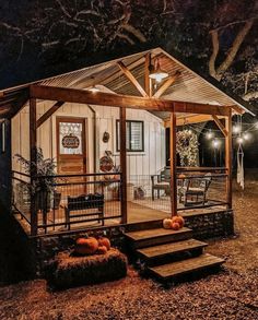 a small cabin is lit up at night with lights on the porch and steps leading to it