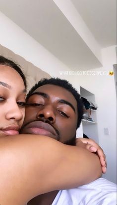 a man and woman embracing each other in the living room with white walls behind them