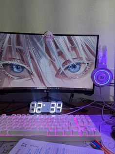 a desktop computer with an alarm clock on the keyboard and headphones next to it