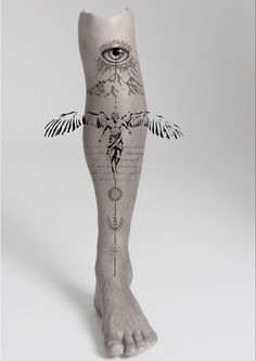 a person's legs with tattoos on them and an eye in the background,