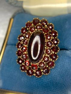 Antique Victorian Garnet Ring with a large oval garnet in the center surrounded by a halo of smaller rose cut garnets. The shank is made of 14k yellow gold, and the top piece is 14k gold filled. Size: 6.5 Weight: 6.4 grams Victorian Oval Garnet Ruby Ring, Oval Garnet Cluster Ring As A Gift, Red Oval Garnet Cluster Ring, Oval Red Garnet Cluster Ring, Elegant Oval Garnet Cluster Ring, Antique Garnet Oval Rings, Antique Oval Garnet Ring, Classic Oval Garnet Cluster Ring, Heirloom Oval Garnet Cluster Ring