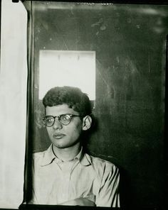 an old black and white photo of a young man with glasses looking at the camera