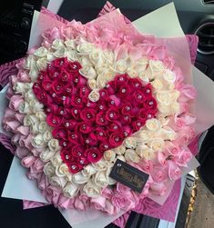 a large heart shaped arrangement with roses and pearls in the shape of a heart on top of a car dashboard