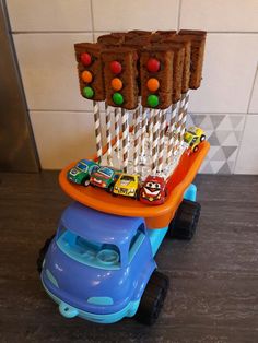 a toy truck with cars on it is parked in front of a wall that has candy bars hanging from the top