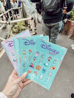 someone holding up some disney stickers in front of people walking down the street together