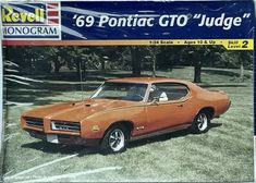 an orange pontiac gto judge car sitting in a parking lot next to some trees