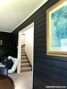 a living room with black walls and white carpeted stairs leading up to the second floor