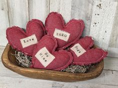 four red heart shaped pillows in a wooden bowl