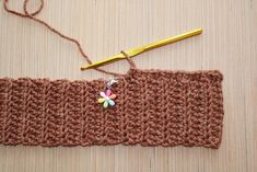 a crocheted piece of cloth with a small flower on it and a pair of scissors next to it