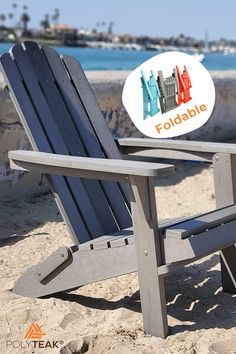 a wooden lawn chair sitting on top of a sandy beach next to the ocean with an orange and blue sign that reads foldable