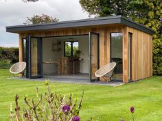 a garden room with two chairs in the grass