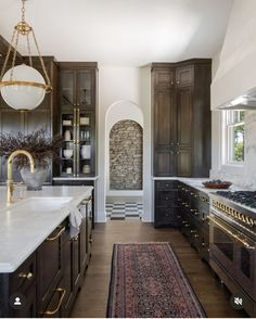 a large kitchen with wooden cabinets and marble counter tops, along with a rug on the floor