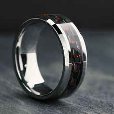 a wedding ring with red lights in the center on a gray surface and black background