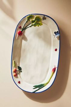 a white plate with blue trim and flowers on the edge, sitting against a wall