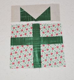 the block is made up of green and white fabric with red flowers on it,