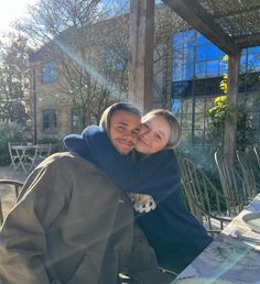 a man and woman hugging each other at an outdoor table