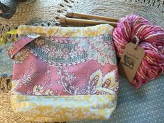 two skeins of yarn sitting on top of a table next to some knitting needles