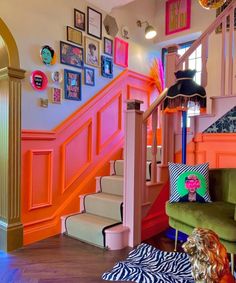 a living room filled with furniture and pictures on the wall next to a stair case