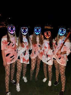 five girls in costumes with masks on their faces and holding baseball bats at night time