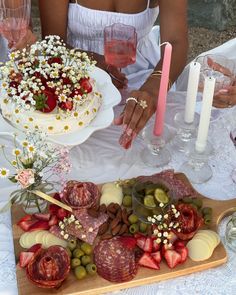 a table topped with lots of different types of food next to wine glasses and candles