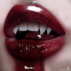 a woman's lips with white teeth and blood dripping from the top part of her mouth