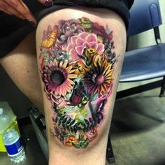 a woman's thigh with flowers on it and a skull in the middle of her leg