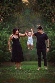 a man and woman holding a baby up in the air