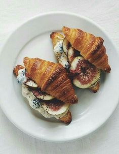 two croissants with blueberries and cream are on a white plate