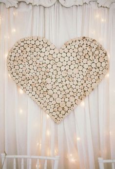 a heart - shaped piece of wood sitting on top of a white curtained wall