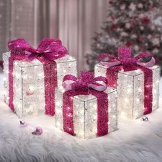 three presents with pink bows and lights on them