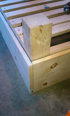 a wooden bed frame sitting on top of a cement floor next to a pair of shoes