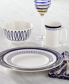 a table topped with plates and cups next to a glass filled with wineglasses