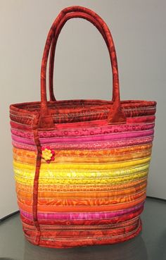 a multicolored handbag sitting on top of a table next to a white wall