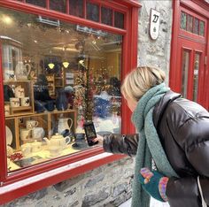 a woman is looking in the window of a store that sells christmas decorations and gifts