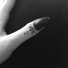 a black and white photo of someone's hand with a small tattoo on it