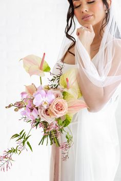 A Bride Holding A Bouquet With A Soft Smile Holding Her Veil.