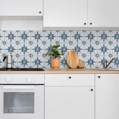 a kitchen with white cabinets and blue tile backsplash