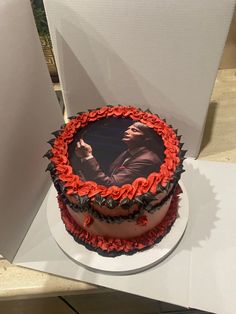 a red and black cake sitting on top of a white table next to a card