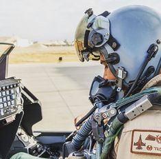 a man sitting in the cockpit of an airplane with a helmet and goggles on