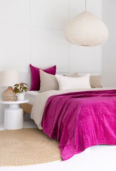 a bedroom with white walls and pink bedding