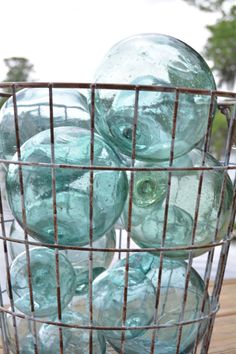 a metal basket filled with lots of green glass bottles on top of a wooden table